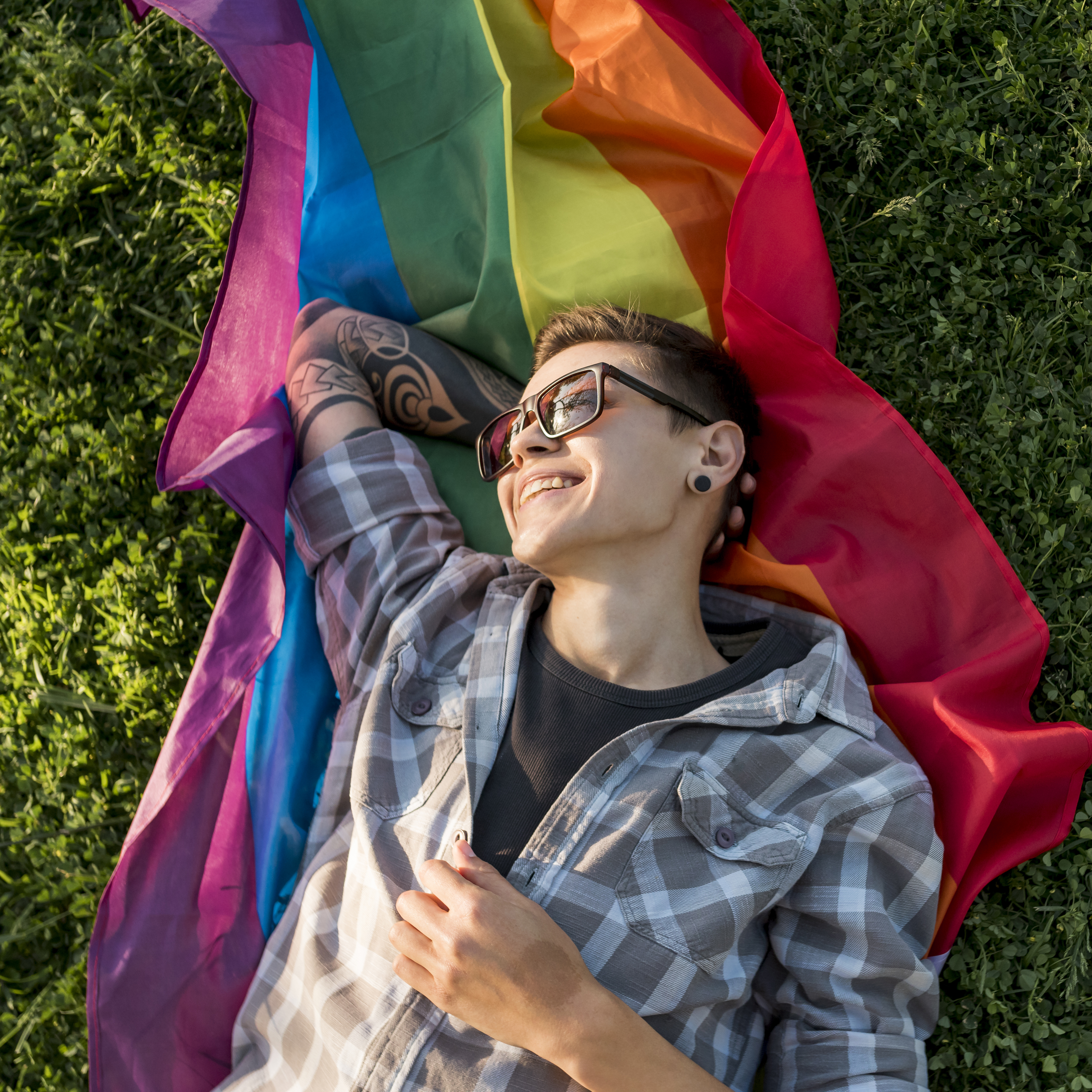 Person laying on the grass with a rainbow flag